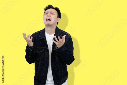 young asian man showing frustrated and stressful moment in yellow isolated background