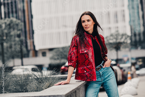 Urban street style featuring a fashionable woman in a red patterned jacket and jeans enjoying a casual outdoor day