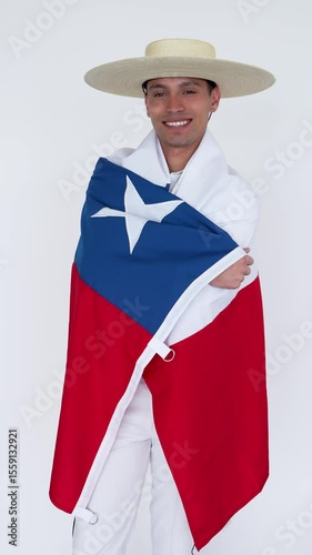 Chilean dancer wearing traditional huaso clothing holds the chilean flag on a white background	
