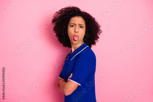Funny young girl in casual blue polo poses against a pink background while making a playful and lively expression