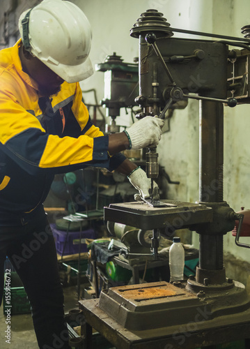 Industrial engineer technician worker man with helmet and uniform safety vest look hand holding steel drilling machine inspection quality control production in side manufactory industry technology