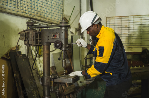 Industrial engineer technician worker man with helmet and uniform safety vest look hand holding steel drilling machine inspection quality control production in side manufactory industry technology
