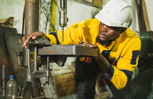 Industrial engineer technician worker man with helmet and uniform safety vest look hand holding steel drilling machine inspection quality control production in side manufactory industry technology