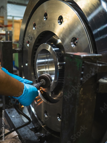 Close-up engineer technician craftsman one person hand wear glove safety protective holding tool cut drill grinding steel with light spark for job repair product in machine workshop industrial factory