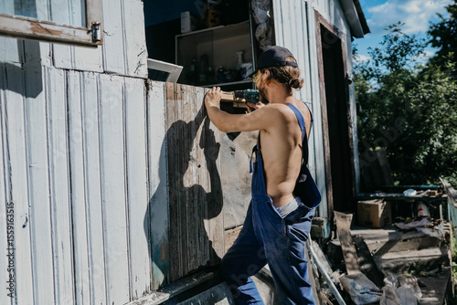 male builder restores old wooden house, replacing boards