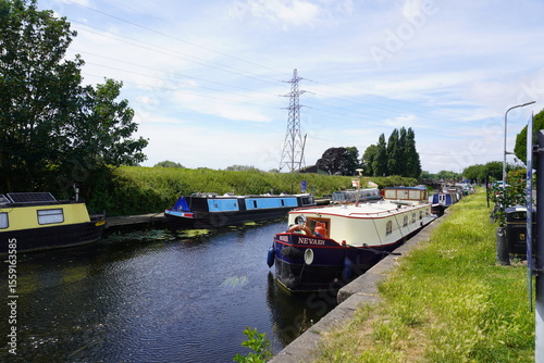 Nottinghamshire, England - June 20 2025: Tranquil scene of narrowboats moored along Beeston Canal with lush greenery and scenic towpath
