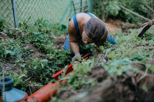 male plumber lays sewer pipe into the ground