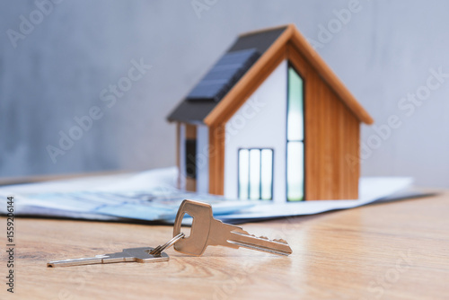 Miniature home with solar panels, keys and deeded dollars. Real estate deal concept, eco-friendly housing and green energy investment.