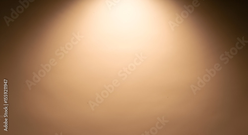 Warm golden spotlight shining on a smooth brown gradient background. Abstract studio lighting concept for product display.