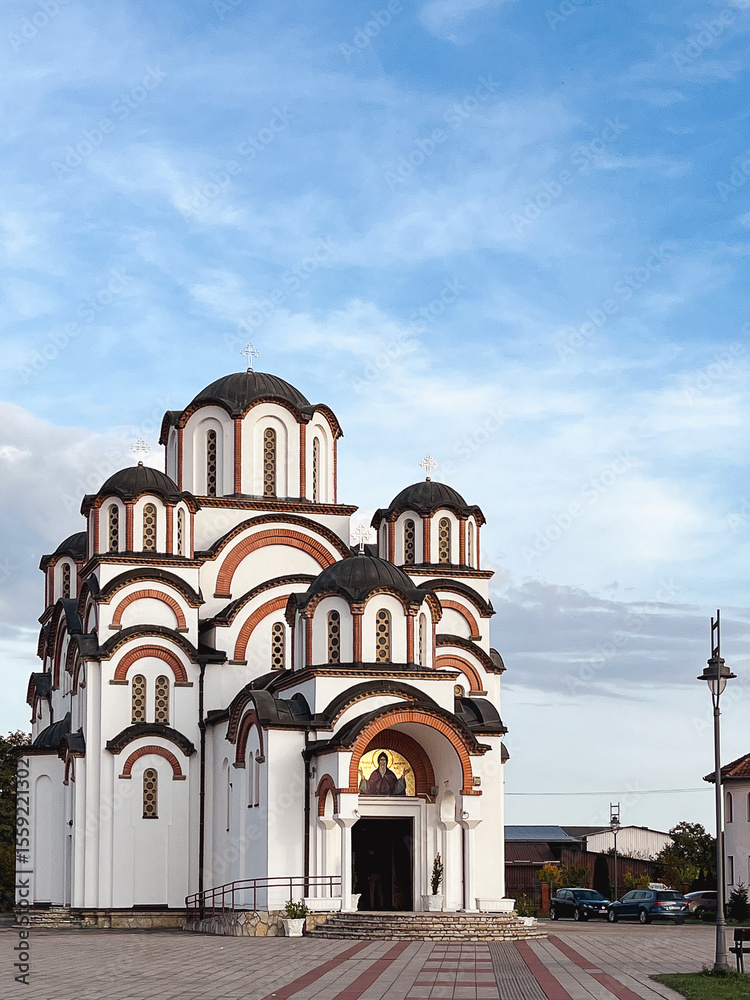 Obraz premium White orthodox church with red brick arches under blue sky