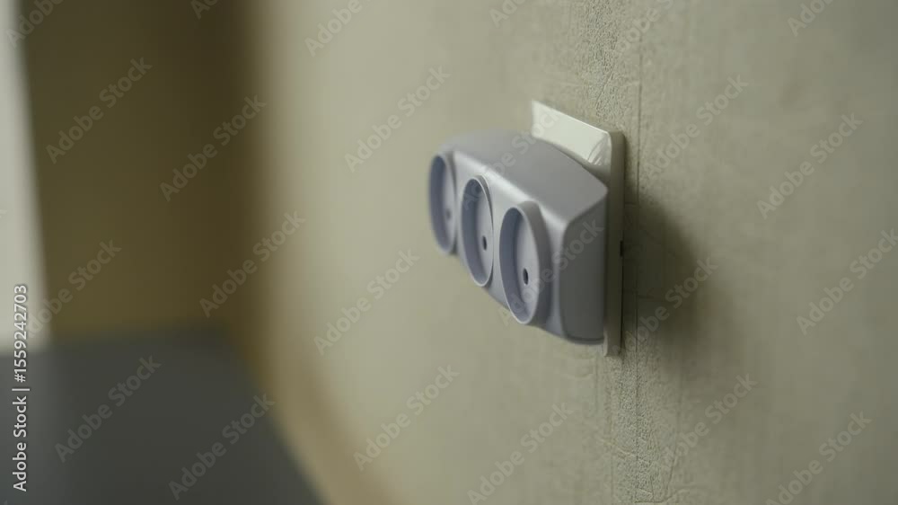 Close-up of unrecognizable man removing tee outlet from wall socket at home. Concept of disconnection process and emphasizing electrical safety measures, closeup. Shooting in slow motion.