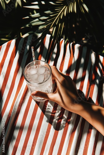 Refreshing Drink Held on Striped Fabric With Tropical Influences in Bright Su...
