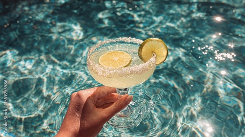 Refreshing Margarita Cocktail Served by a Hand Beside a Sparkling Pool on a S...