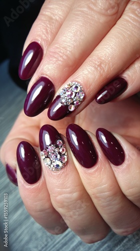 Elegant Dark Purple Nails With Decorative Crystals at a Nail Salon
