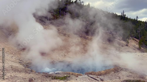Scenic landscape view of a pool of boiling hot water and steam being forced out of a fumarole at the Beryl Spring in Yellowstone National Park