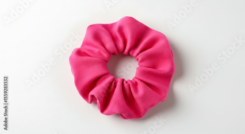 A bright pink fabric scrunchie, a popular retro hair accessory, isolated on a clean white background. A simple, vibrant fashion object for style concepts.
