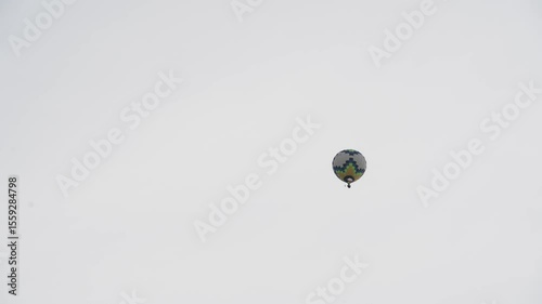 A hot air balloon with a basket flies across the evening sky. The silhouette of a balloon against the background of the evening sky on a white sky.