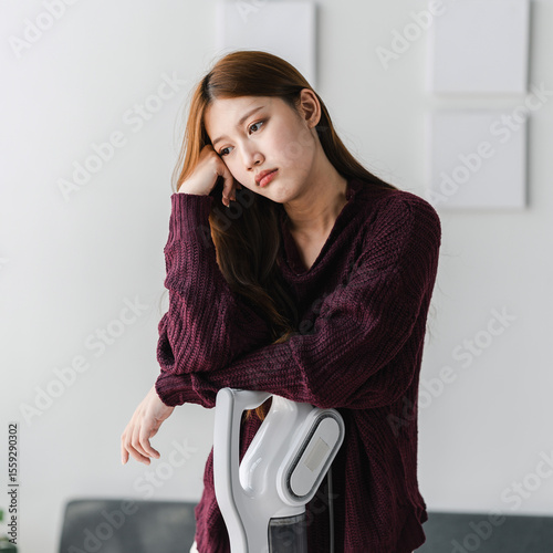Sad Asian Woman Leaning on Vacuum Cleaner at Home Feeling Tired Exhausted After Cleaning Housework Household Chores Housekeeping Bored Frustrated Unhappy