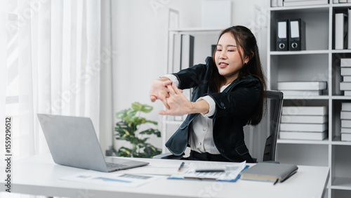 Asian Businesswoman Stretching at Her Office Desk for Relaxation Relief During Work Hours Promoting Employee Wellness and Preventing Office Syndrome