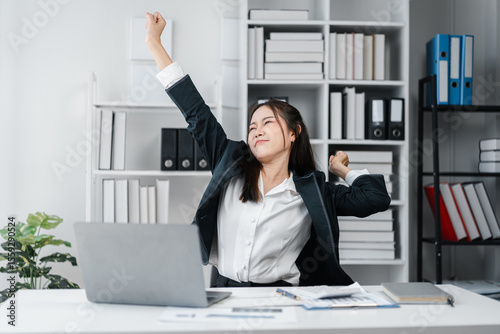 Asian Adult Businesswoman Stretching at Desk after Work From Home at Office with Laptop and Bookshelf for Successful Relax and Wellness