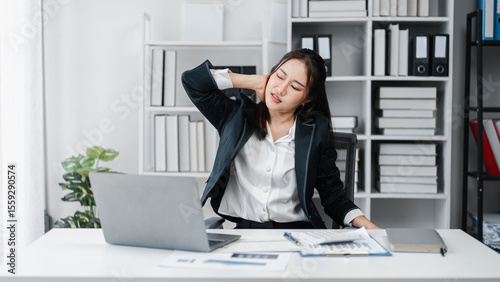 Asian Adult Woman Experiencing Neck Pain While Working at Desk Office Job Stressed from Work with Computer Laptop Uncomfortable Posture Problem Healthcare Concept