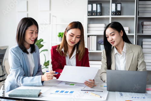 Three women are sitting at a table with a white piece of paper in front of them