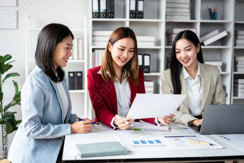 Three women are sitting at a table with a white piece of paper in front of them