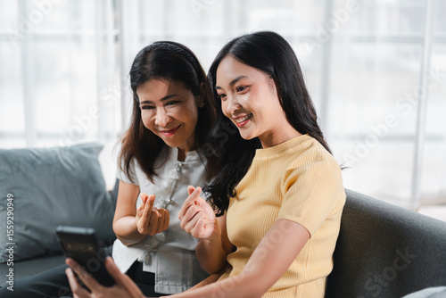 Asian Women Enjoying Video Call on Smartphone: Family Connection Across Generations Spending Time Together with Love and Care