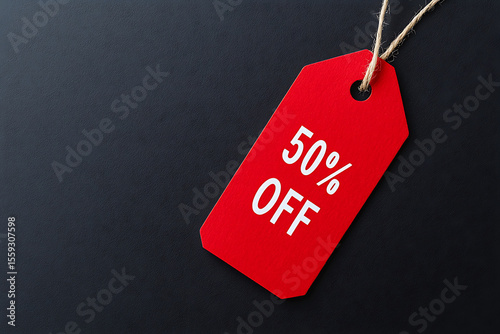 A bright red tag on a black background announces a promotion: 50% off. Tied to a string, it suggests a sale, bargain, or shopping discount offer.