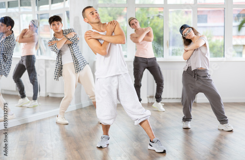 During hip hop dance lesson, guy leads, conducts classes, teaches students to correctly perform elements and sequence of movements