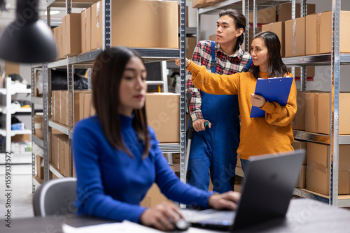 Asian employee using crutches to walk in storage room and manage orders for distribution. Small business supporting local delivery, business logistics and accessible warehouse operations.