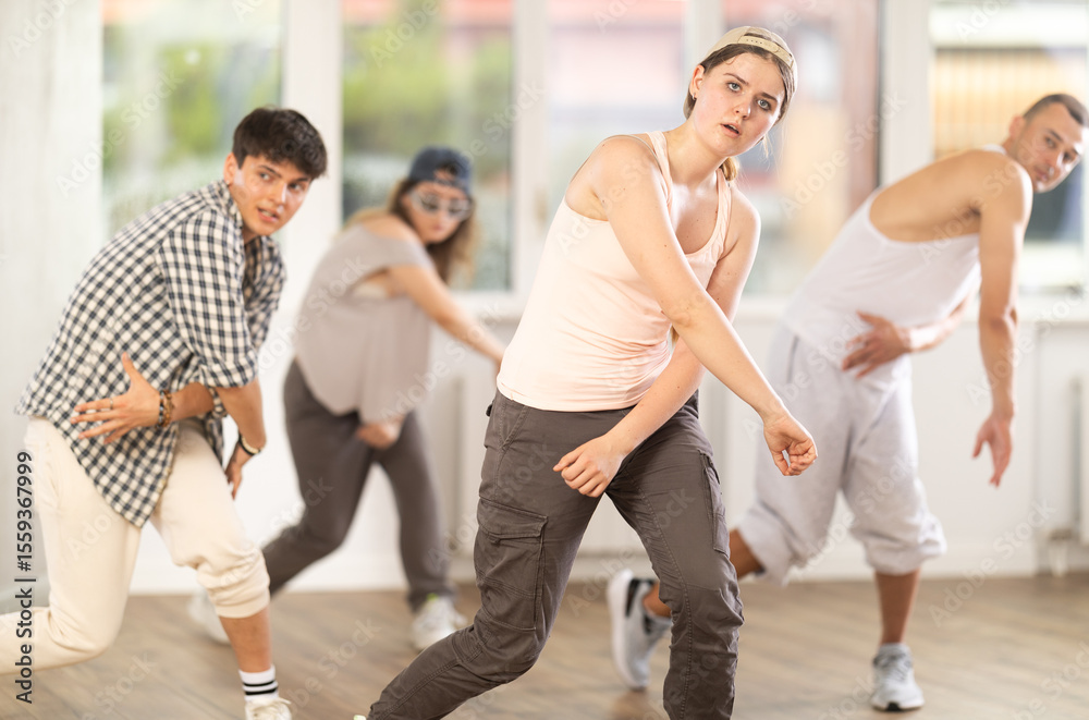 Obraz premium Girl makes movements and teaches group of hip hop fans to move beautifully and confidently to music, to control their bodies. Young boys and girl repeat after teacher