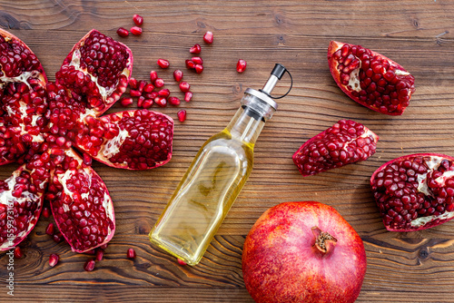 Glass bottle of pomegranate seed oil in a glass bottle and fresh fruit on a table, top view