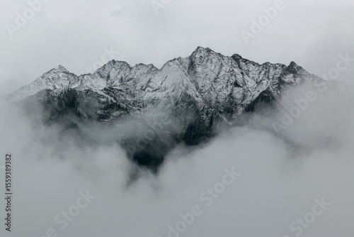 Snowy Mountain Peaks Emerging Through Thick Fog