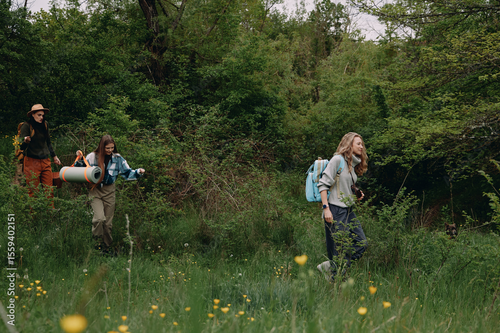 Obraz premium Middle aged woman hiking outdoors with two companions in lush green forest, enjoying active and healthy lifestyle focused on fitness and wellbeing in nature.