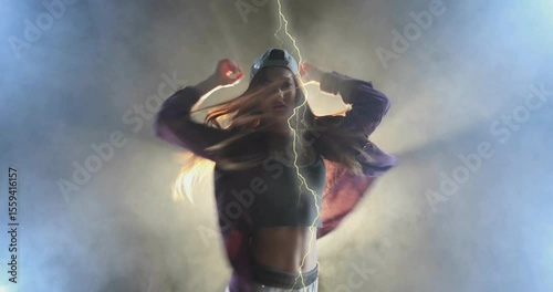 Dancer emerging from backlit fog, spinning, raising arms responding to lightning strike for show