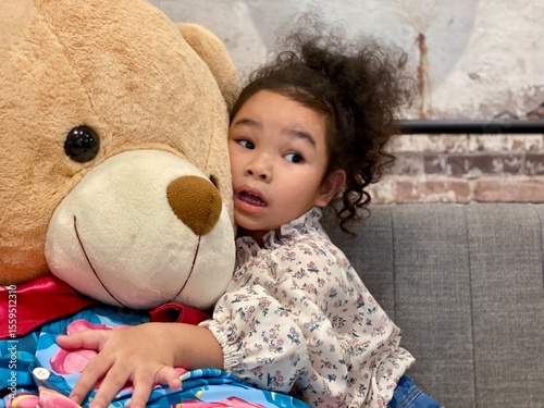 Cute little girl playing with a teddy bear on the sofa