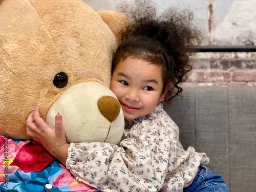 Little girl with a teddy bear in the living room at home