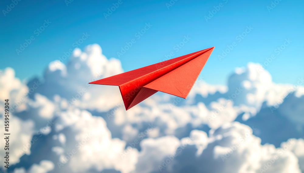Fototapeta premium A red paper airplane soars through a bright blue sky, surrounded by fluffy white clouds, symbolizing freedom and creativity