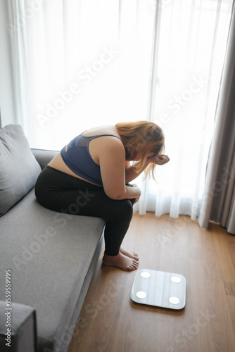 Sad fat woman with fat upset bored of dieting Weight loss fail  Fat diet and scale sad Obese asian female on weight scale at home weight control