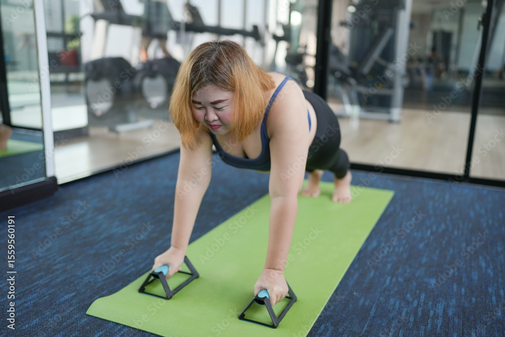 Fototapeta premium Overweight woman exercising for weight loss. plank exercise in stretching positions on mat yoga at gym Cheerful&nbsp;Fat woman diet healthy lifestyle