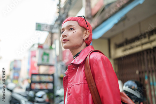 Gen z girl leather fashion with punk Asian woman tourist of local city Southeast Asia travel trendy pink hairstyle young female punk traveler walking around in town