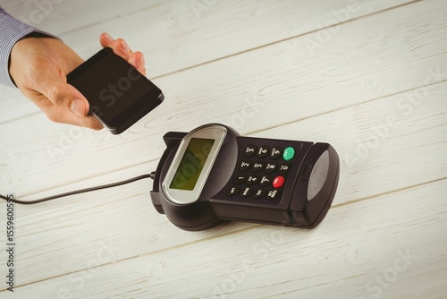 Contactless payment is happening on wooden countertop in flat design, with smartphone and terminal