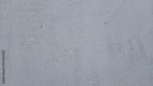 Textured Grey Wall: The image reveals a textured wall with visible imperfections, offering a minimalist yet compelling visual experience.
