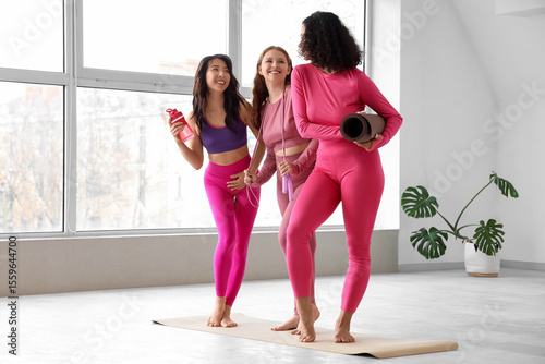 Young body positive women with sports equipment at gym