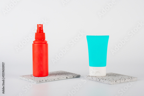 Plastic white tube for cream or lotion. Skin care or sunscreen cosmetic, Cosmetic red bottle. Womens cosmetic accessory for makeup with stylish props on white background.