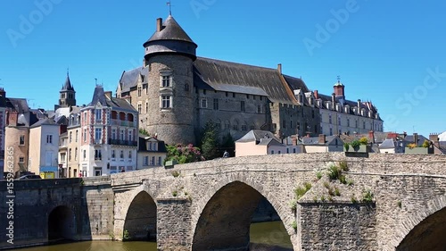 Walking view of the historic Pont Vieux aka Old Bridge with fortified medieval Laval Castle in the background, Laval, Mayenne, France.