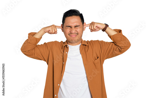 Tablou pe pânză Irritated young Asian man in casual shirt plugging ears with fingers, disturbed