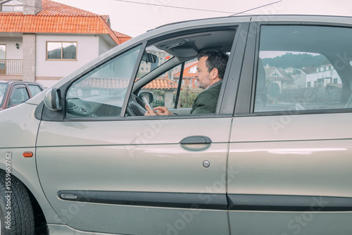 middle-aged man checking his cell phone in the car
