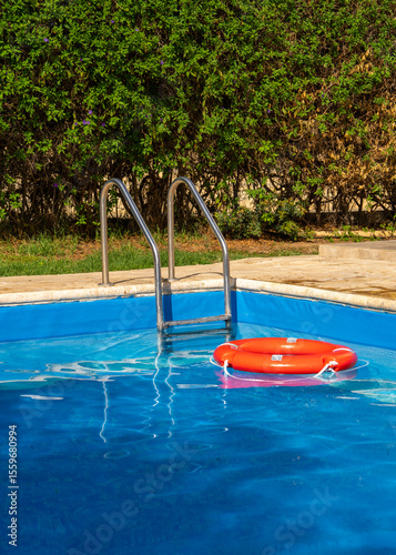 Lifebuoy floats in blue swimming pool, symbolizing water safety and summer relaxation. Ideal for travel, rescue services, and poolside vacation designs.